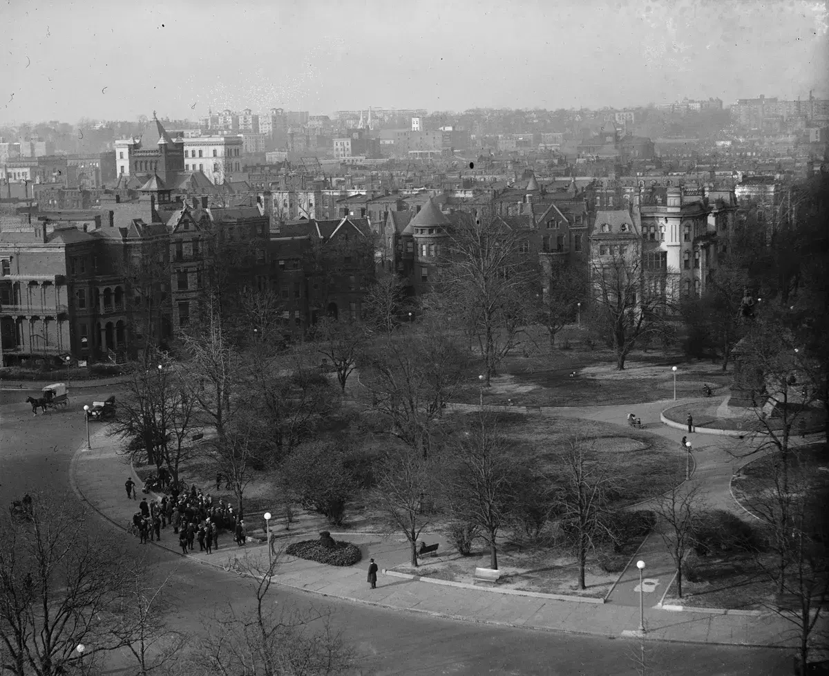 Logan Circle seen from above with bare trees, Victorian houses around the park and a church tower at left