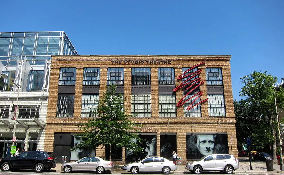 The Studio Theatre's three-story tan brick building with large industrial windows and a red neon sign