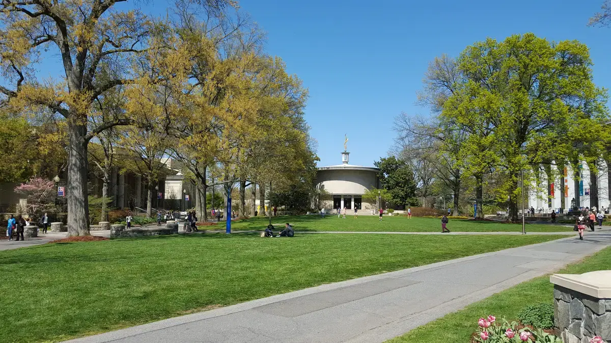 American University main quad in spring: green lawn, students, AU banners, Kay Spiritual Life Center at center