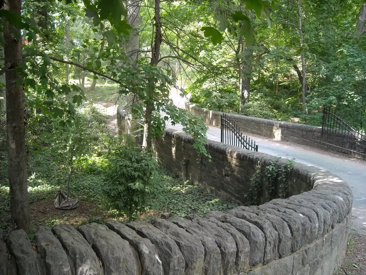 The stone-walled entry drive and iron gates of the Tregaron estate under tree canopy, Washington, D.C.