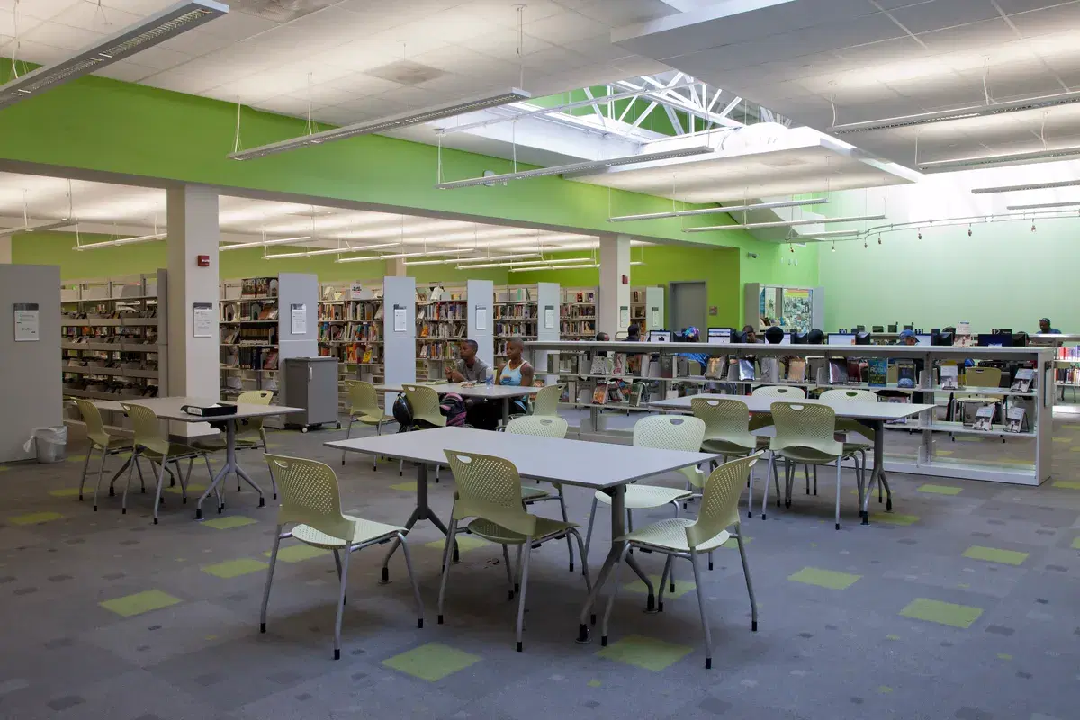 The Deanwood library reading room, with tables, lime-green walls and book stacks