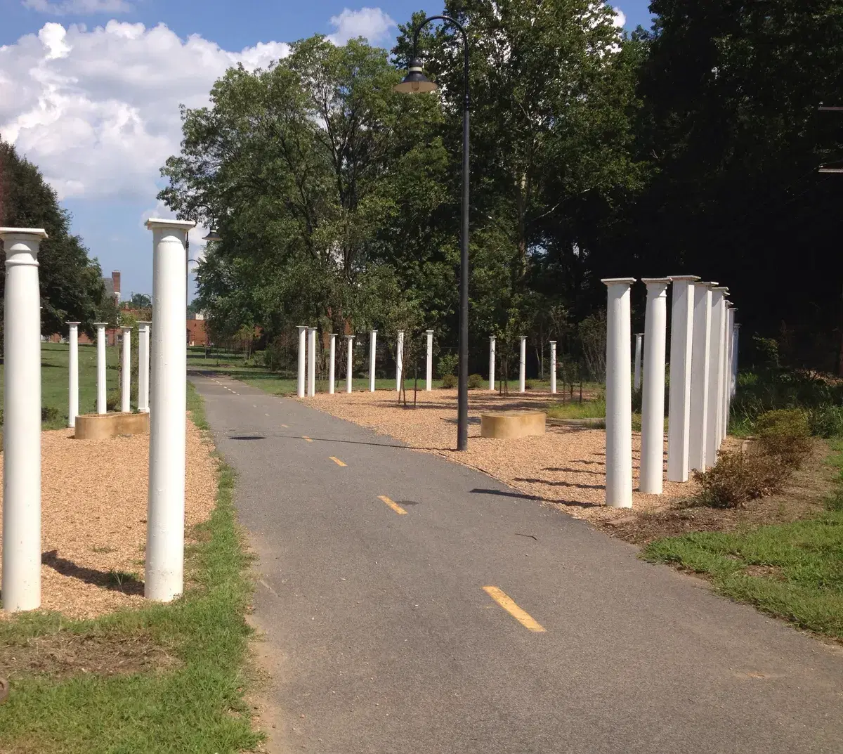 The paved Marvin Gaye Trail passing rows of white columns at Peanut Park, under trees