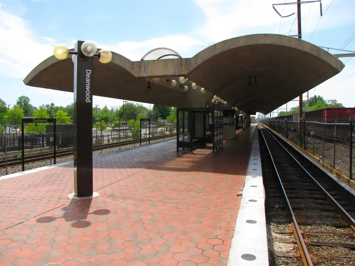 The Deanwood station platform under its curved concrete canopy, with the station name on a pylon