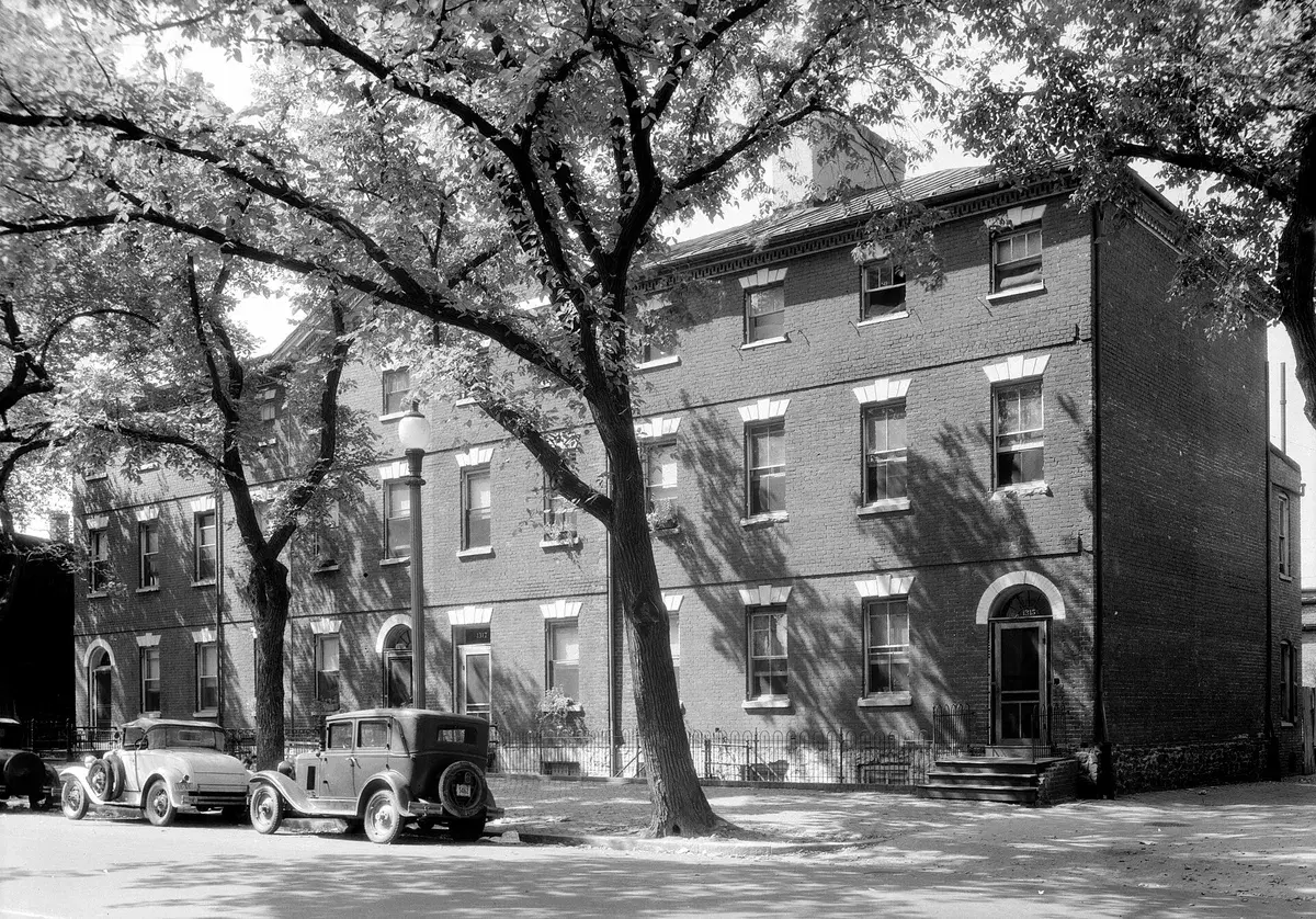 Wheat Row, a three-story brick row of houses behind street trees, with two 1930s cars parked in front