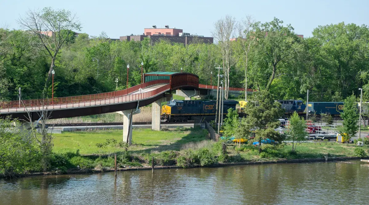 The Anacostia Riverwalk Trail's red footbridge over the railroad in Anacostia Park, with the river in front