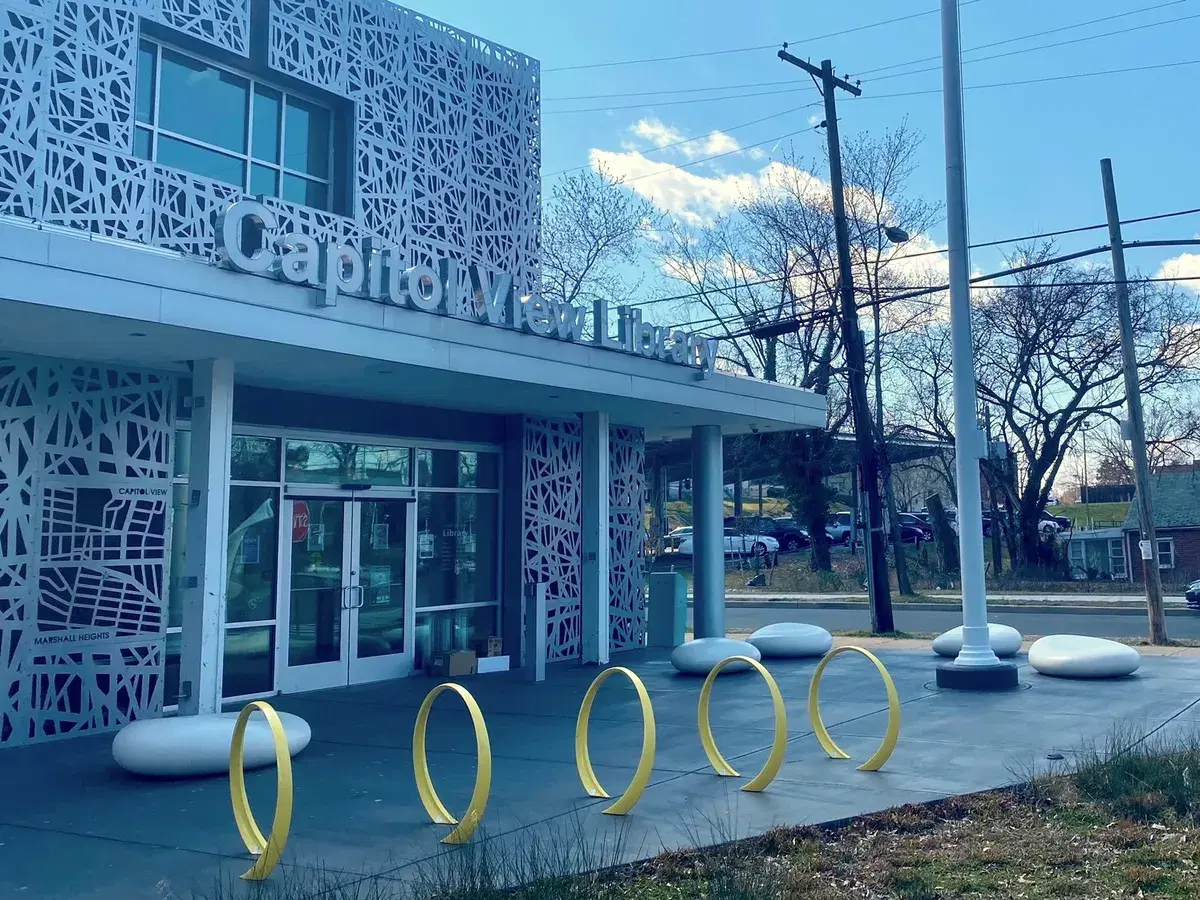 The entrance of Capitol View Library, with a white patterned screen facade and gold bike racks