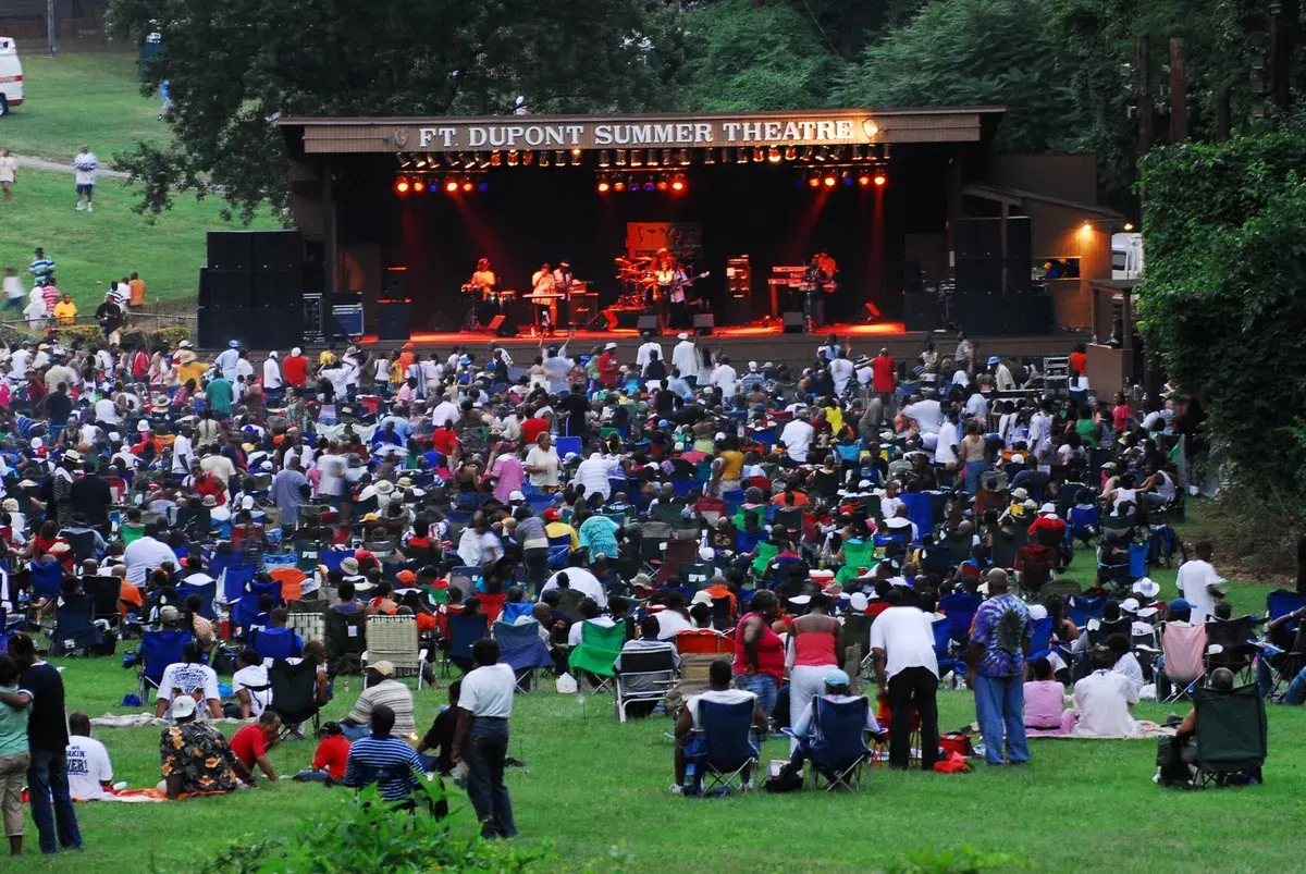 A band on the Fort Dupont Summer Theatre stage before a large crowd on the lawn