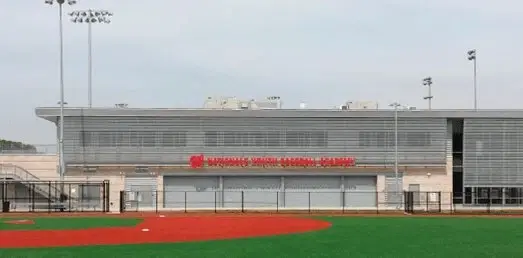 The Nationals Youth Baseball Academy clubhouse, with its red sign, behind a turf baseball field