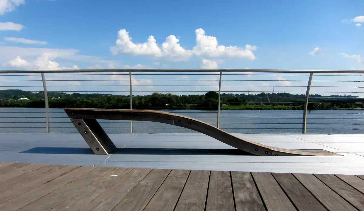 A sculptural wooden lounge chair on the Yards Park boardwalk overlooking the Anacostia River, Washington, D.C.