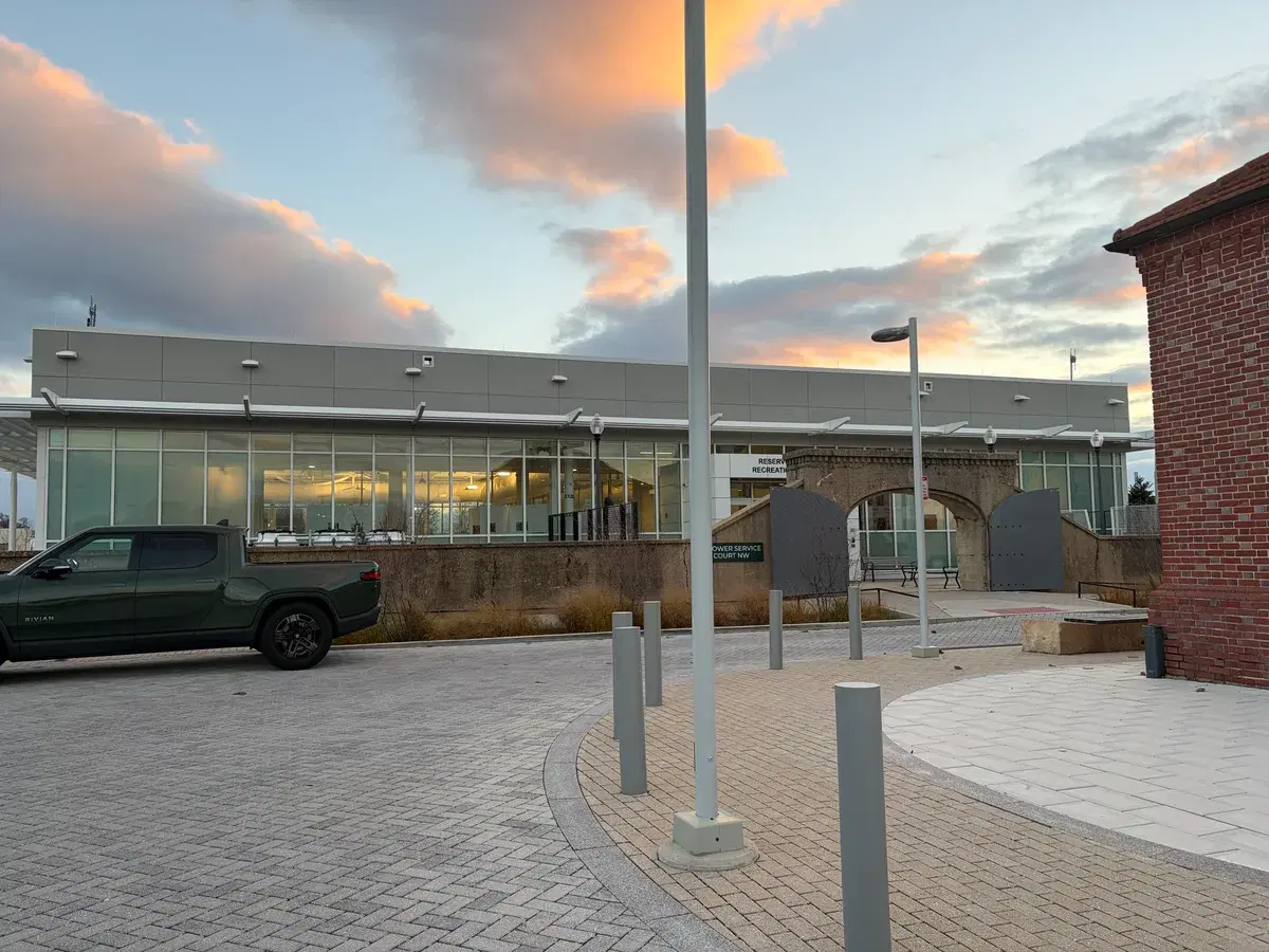 The glass-fronted Reservoir Park Recreation Center behind a restored stone gateway at sunset