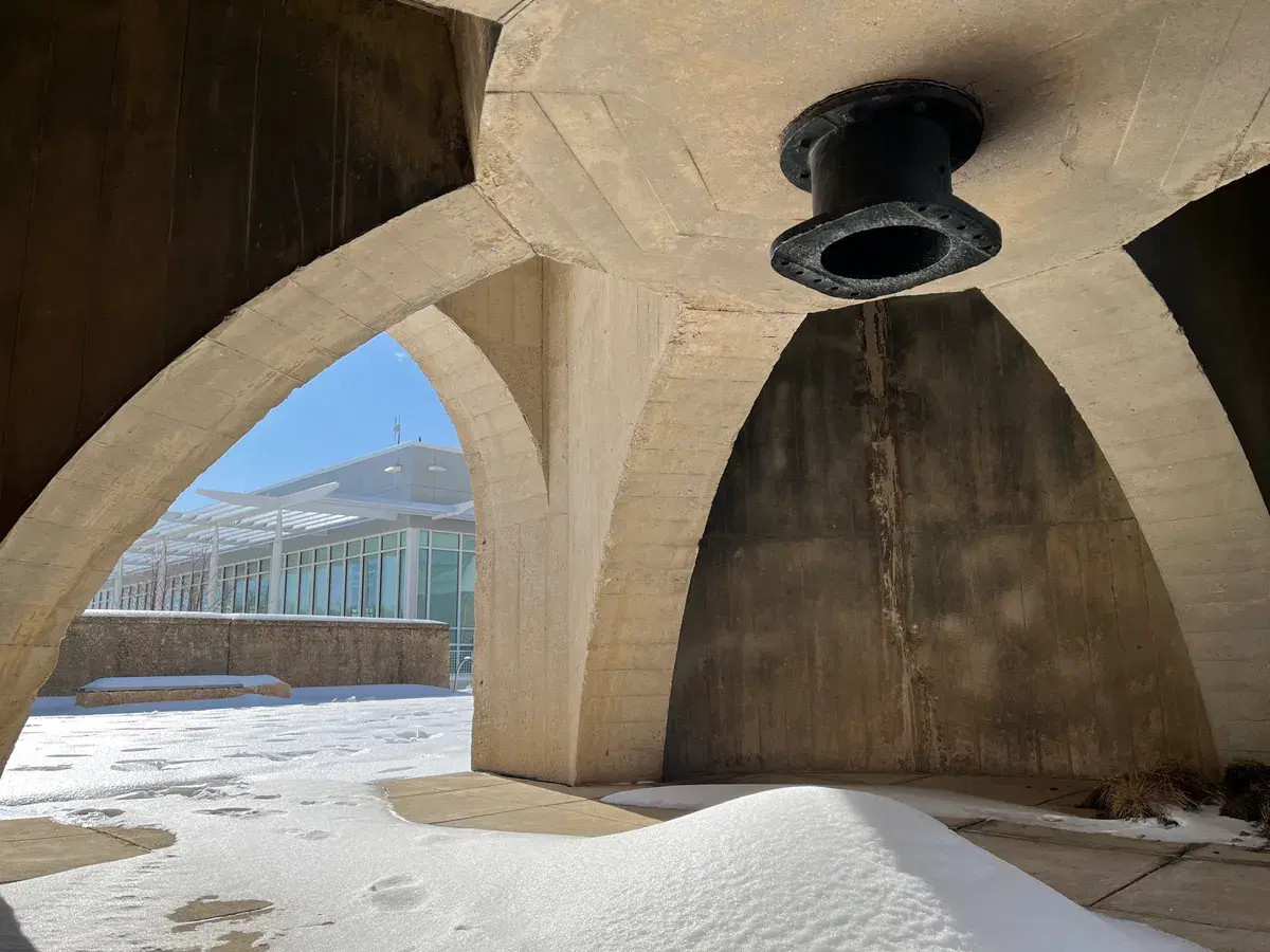 View from inside a concrete sand bin, through its arched openings, to the snow-covered plaza and the recreation center