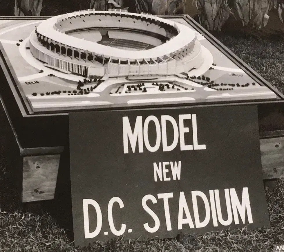 Architectural model of the round stadium behind a sign reading Model New D.C. Stadium