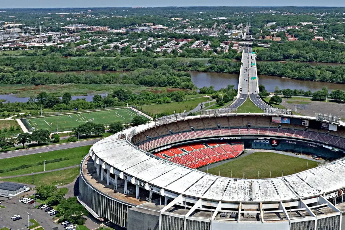 Aerial view of the closed RFK Stadium, a turf field to its left, the Whitney Young Bridge and the Anacostia beyond