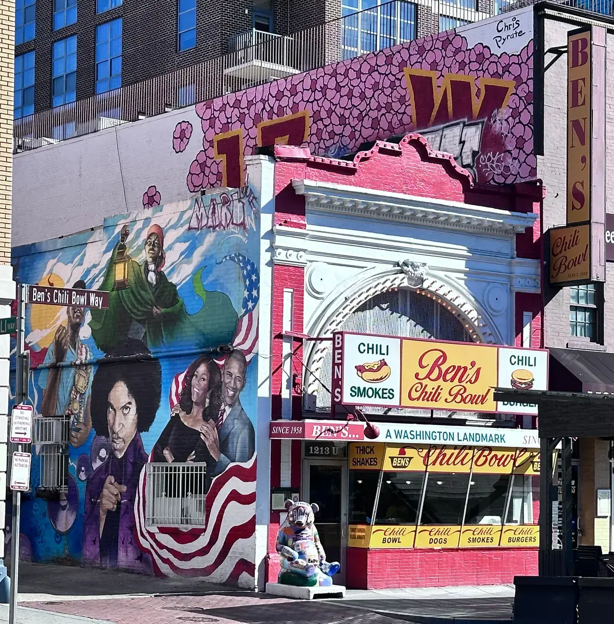 Daytime storefront of Ben's Chili Bowl on U Street with the adjacent mural (Obamas, Prince) and Ben's Chili Bowl Way street sign