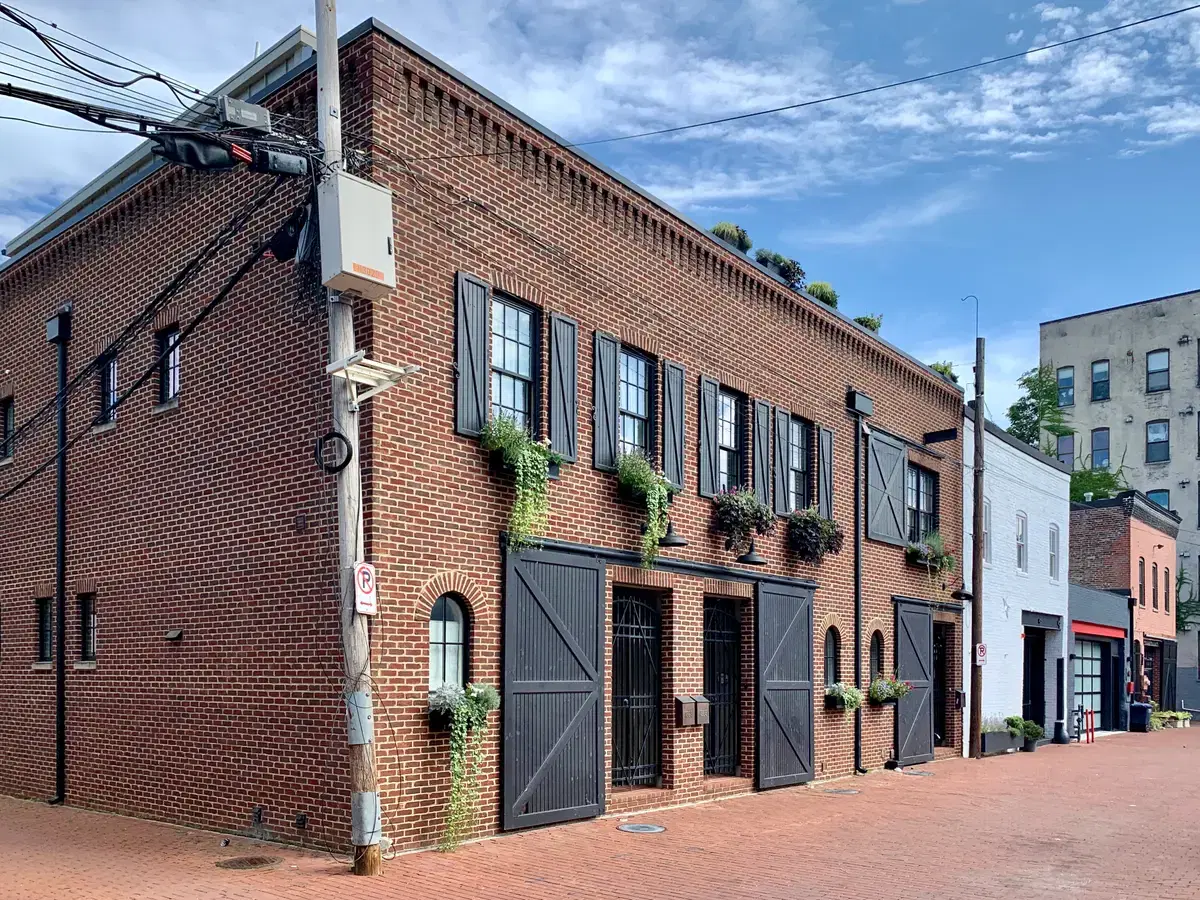 A restored brick carriage house with black shutters and window boxes in Blagden Alley, Washington, D.C.