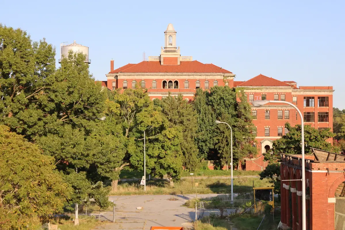The red-brick Nichols Building and historic water tower rising over the trees of the St. Elizabeths campus in golden light, Washington, D.C.