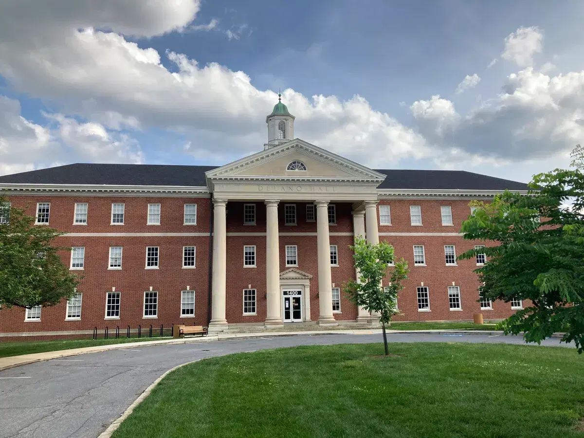 Delano Hall, a brick building with a white columned portico and cupola, now DC International School