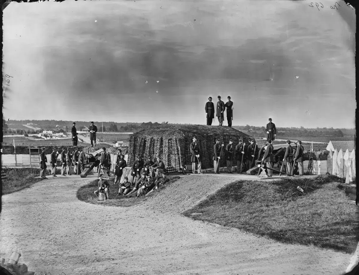 Union artillerymen standing on and beside the earthen walls and guns of Fort Stevens