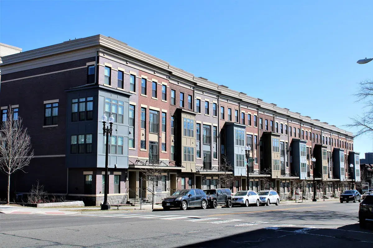 New brick rowhouses along Georgia Avenue NW across from the campus, with cars parked on the street
