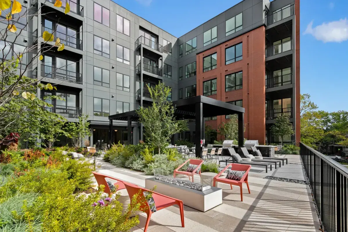 Kite House's landscaped courtyard with lounge chairs and a fire table, the condo building's balconies above