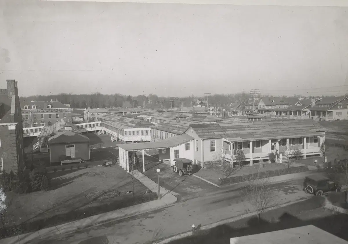 Rows of long wooden ward buildings with covered porches across the hospital grounds