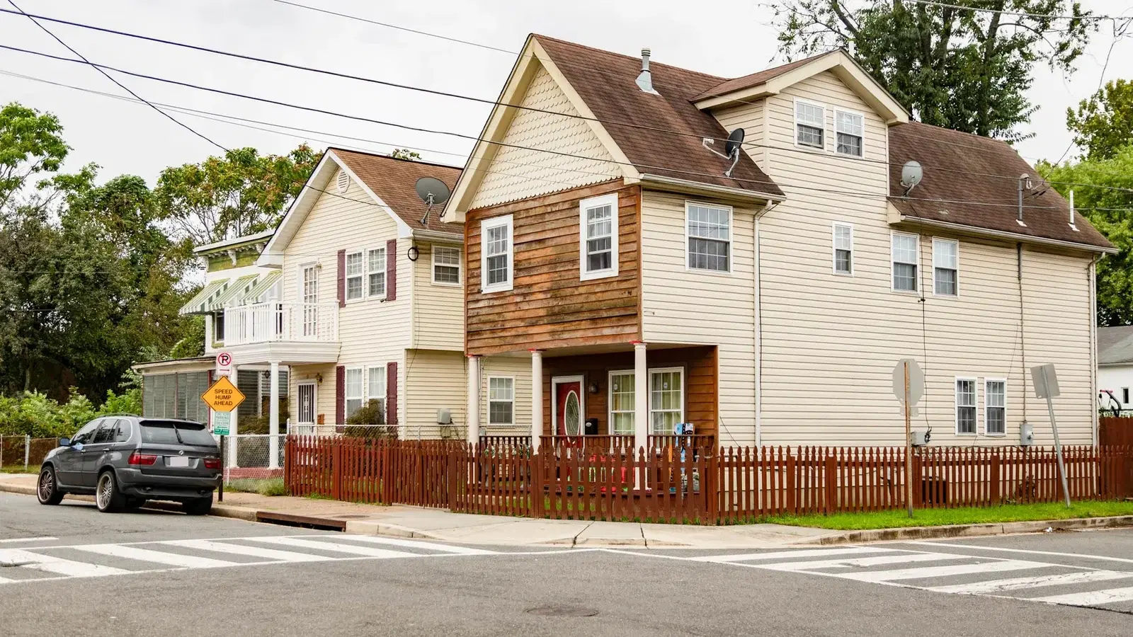 Detached frame houses with gabled roofs, porches and a picket fence on a corner in Deanwood, Washington, D.C.