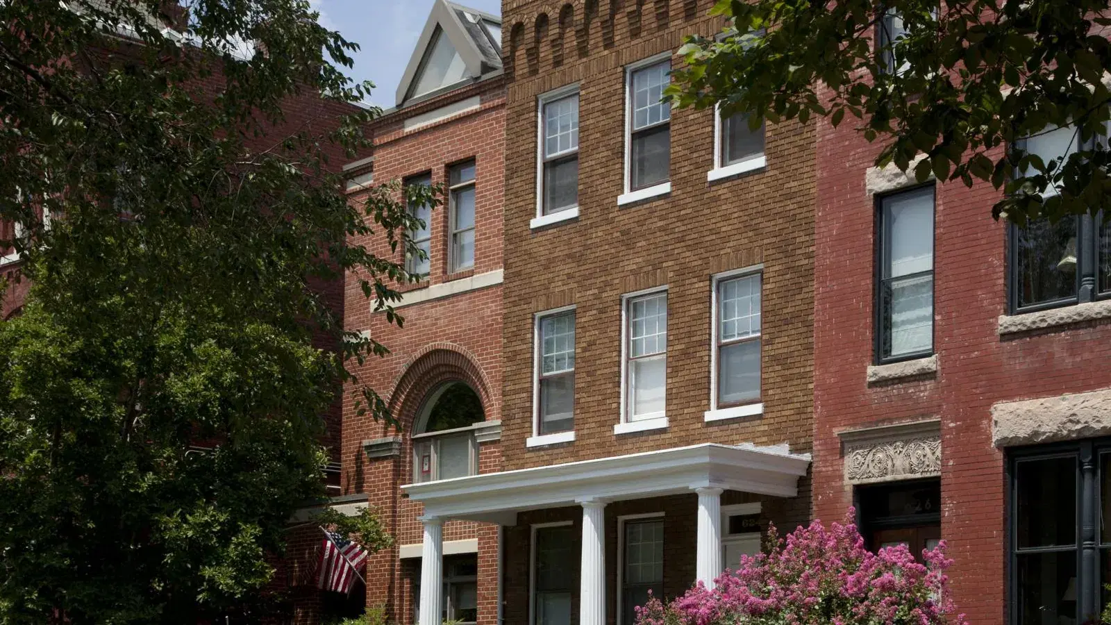 Brick Victorian row houses with a columned portico and crape myrtle in bloom on East Capitol Street, Washington, D.C.