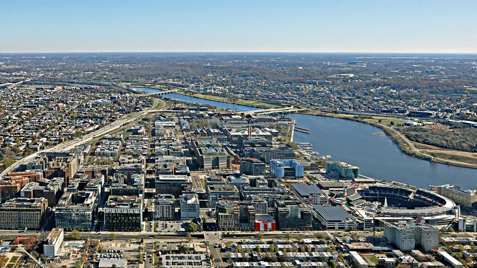 Aerial view of the Navy Yard skyline — new high-rises and their rooftops, Nationals Park, and the Anacostia River with the Frederick Douglass Bridge beyond, Washington, D.C.