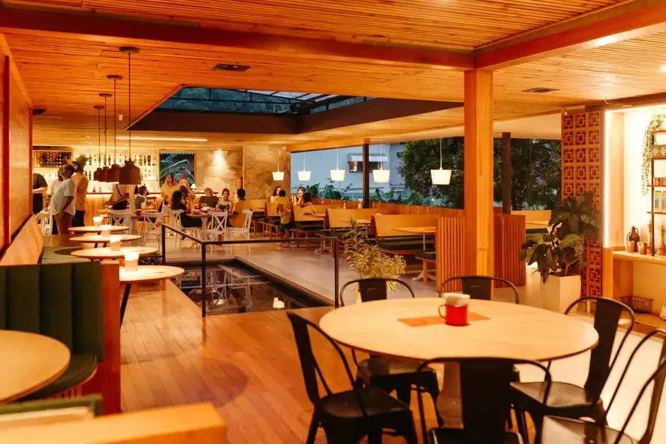 Warm, wood-toned restaurant interior with diners at golden hour — generic dining ambience, no location tells; card is about a restaurant-row vibe