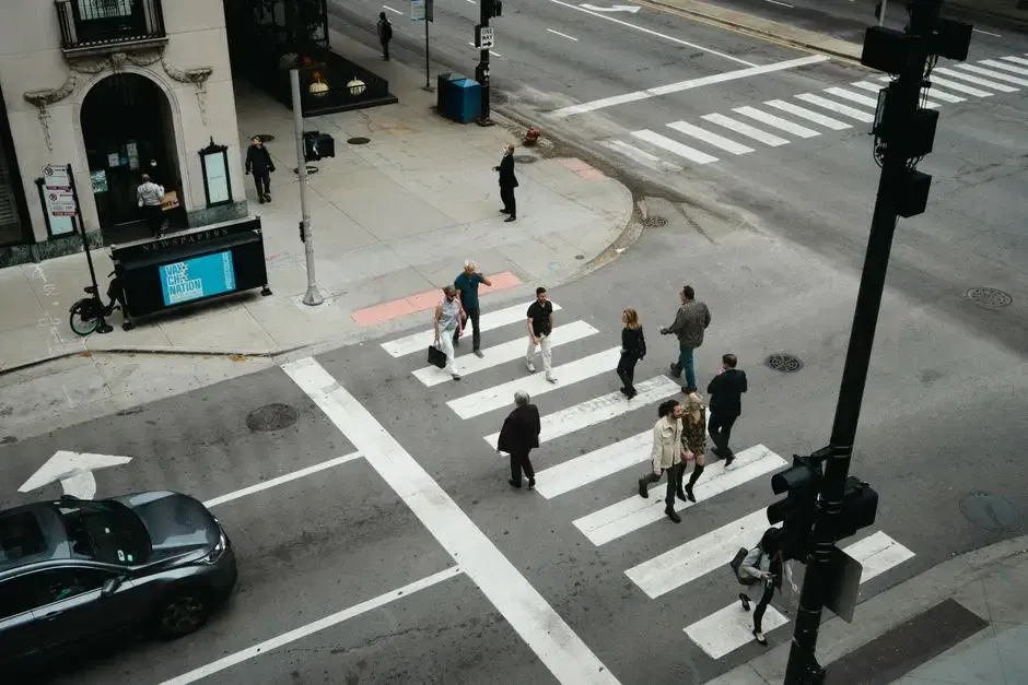 Aerial view of pedestrians crossing a striped urban crosswalk at an intersection