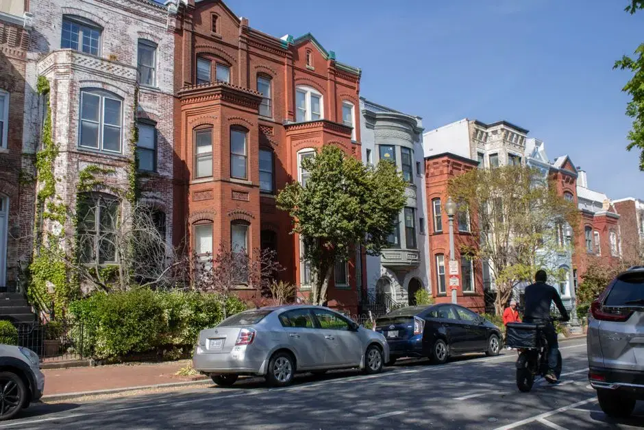 DC brick rowhouses with cars parallel-parked at the curb, sunny day, DC plates