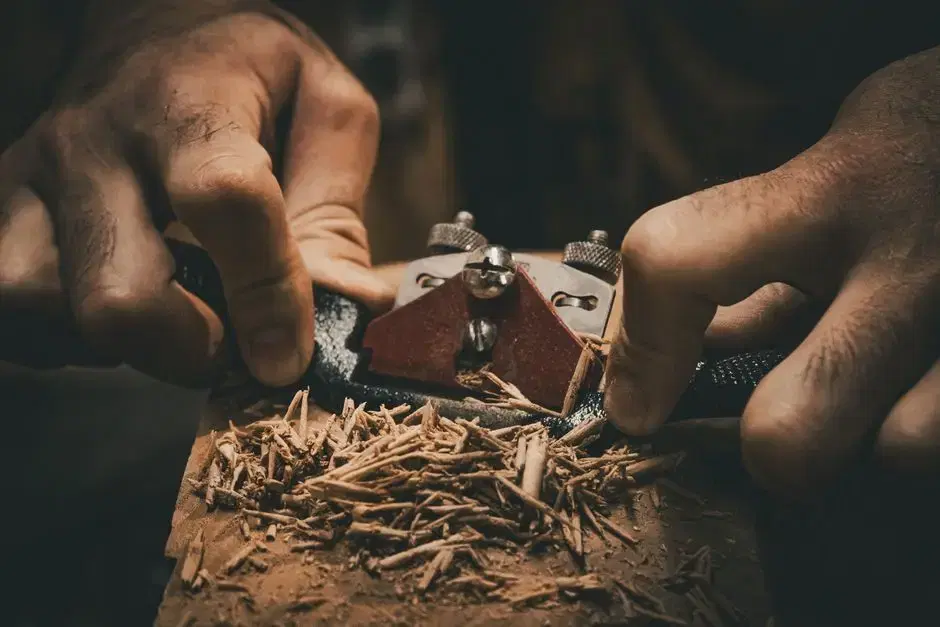 Moody close-up of hands working a hand plane with wood shavings - timeless craftsmanship imagery for the Black-craftsmen-built-homes theme; thematic, not a place claim