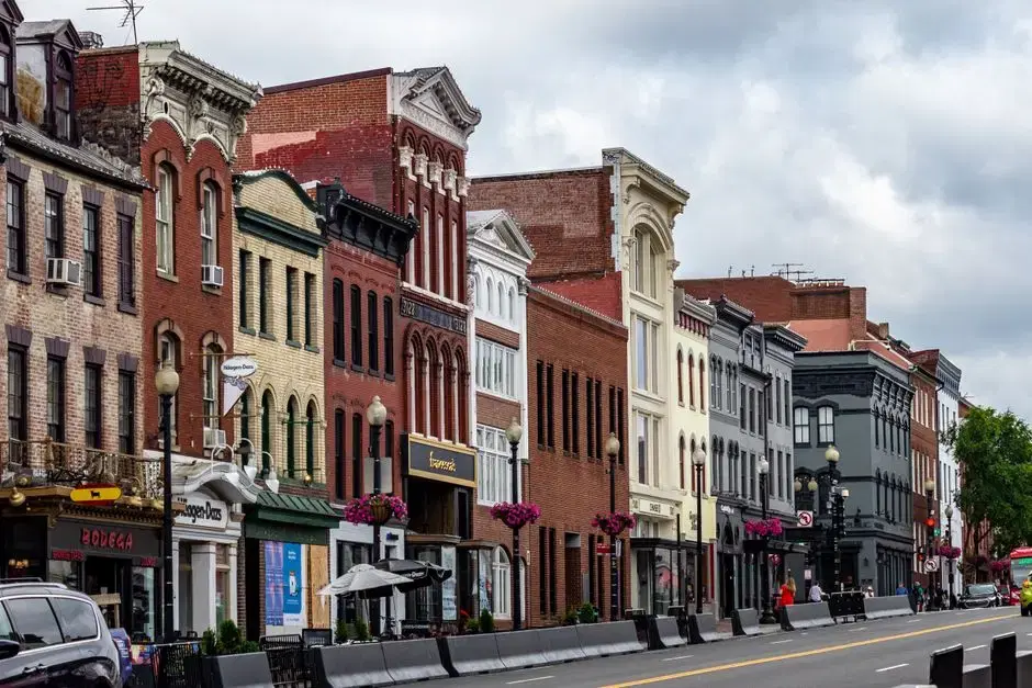 Actual M Street NW Georgetown — brick Federal/Victorian storefronts, street lamps with hanging flower baskets; Pexels alt confirms Georgetown, Washington DC