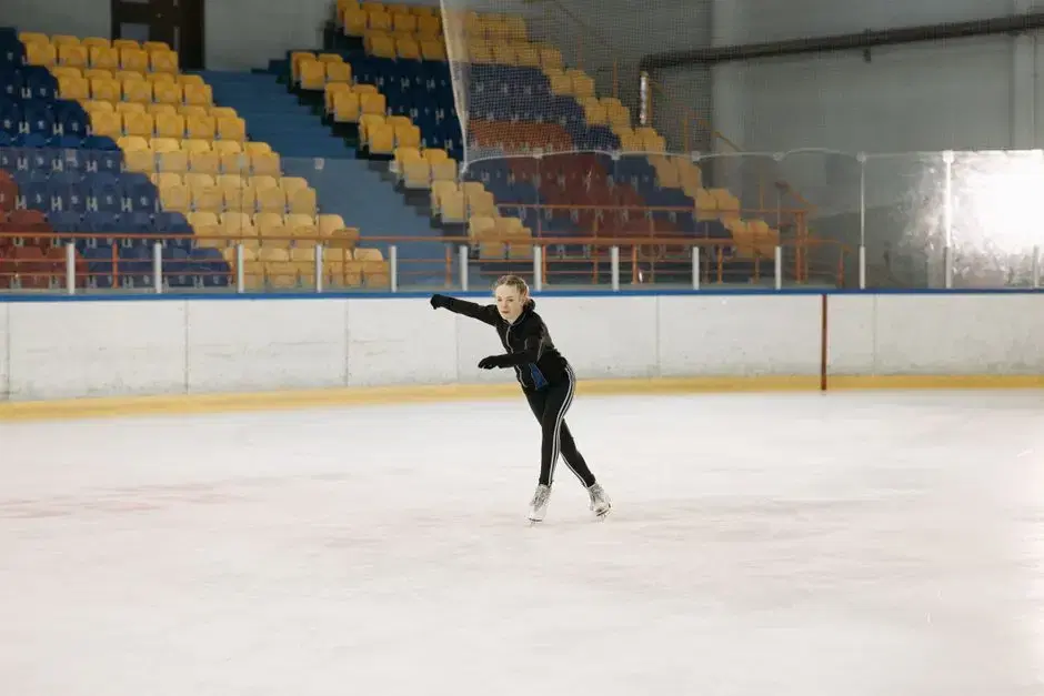 Young figure skater alone on an indoor rink with arena seating — Kids-On-Ice ambience (atmospheric, venue not identified)