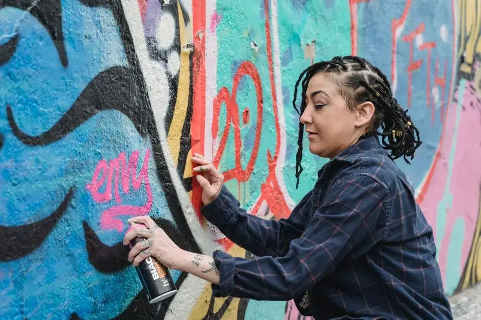 Street artist spray-painting a colorful mural, location-anonymous close-up; thematic arts-scene imagery, does not claim to be the Anacostia Arts Center