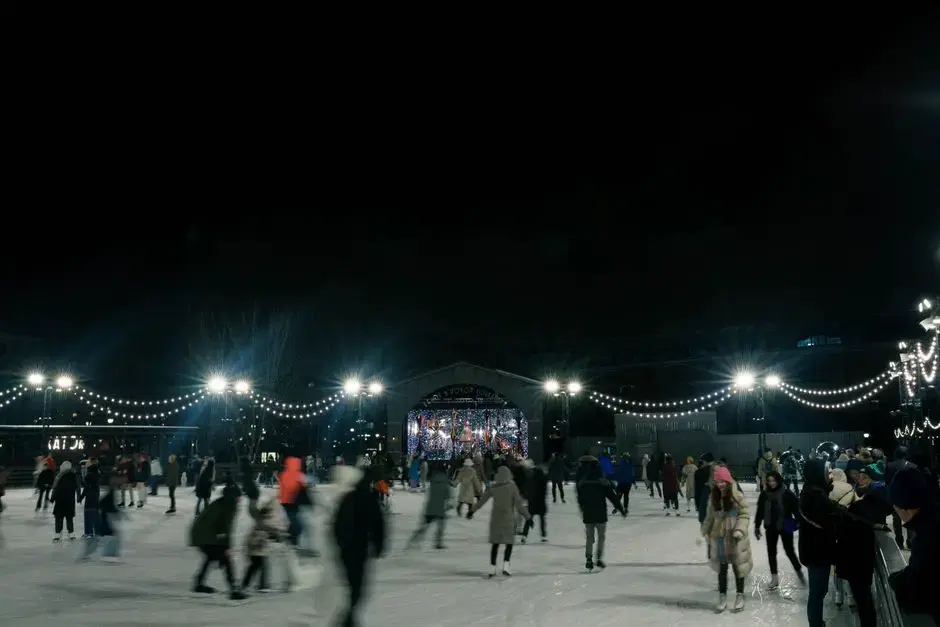 Skaters on an outdoor rink under string lights at night — atmospheric for Canal Park's winter ice rink