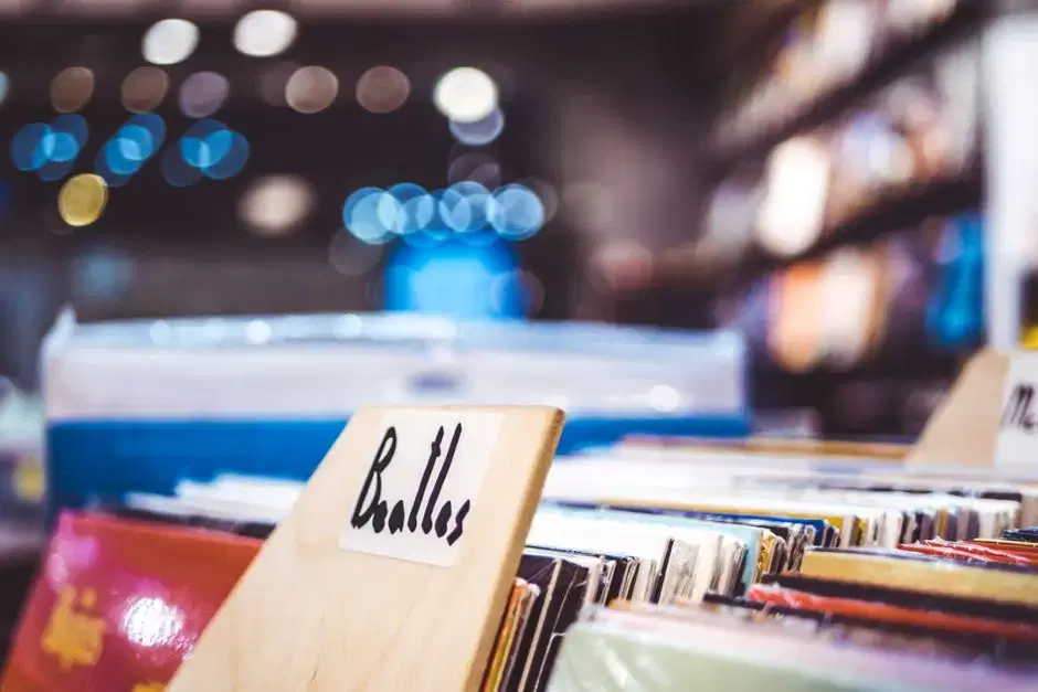 Thematic per brief: record-store bin with handwritten Beatles divider card, vinyl ambience