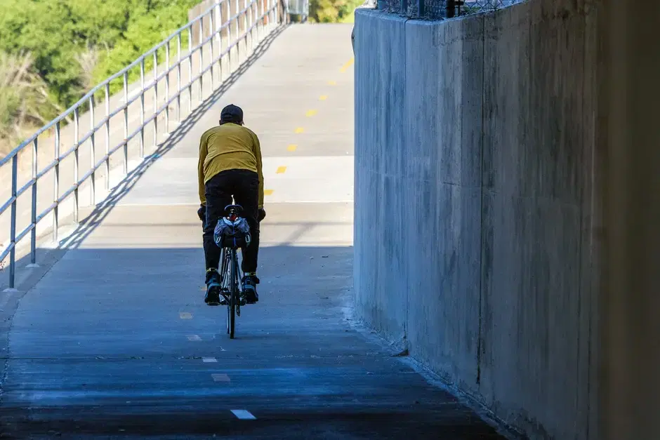 Thematic: cyclist on a dedicated concrete bike path passing under a bridge - matches the paved-bike-highway activity; no identifying landmarks