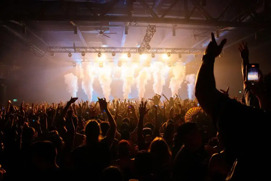 A concert crowd under stage lights and smoke at an indoor music club.
