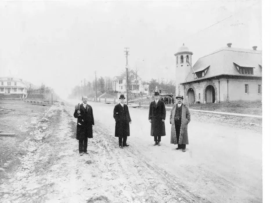 Colonel Arthur E. Randle and three men standing on a then-unpaved Pennsylvania Avenue SE in 1911, with the Chemical Company No. 2 firehouse and its tower at right, Washington, D.C.