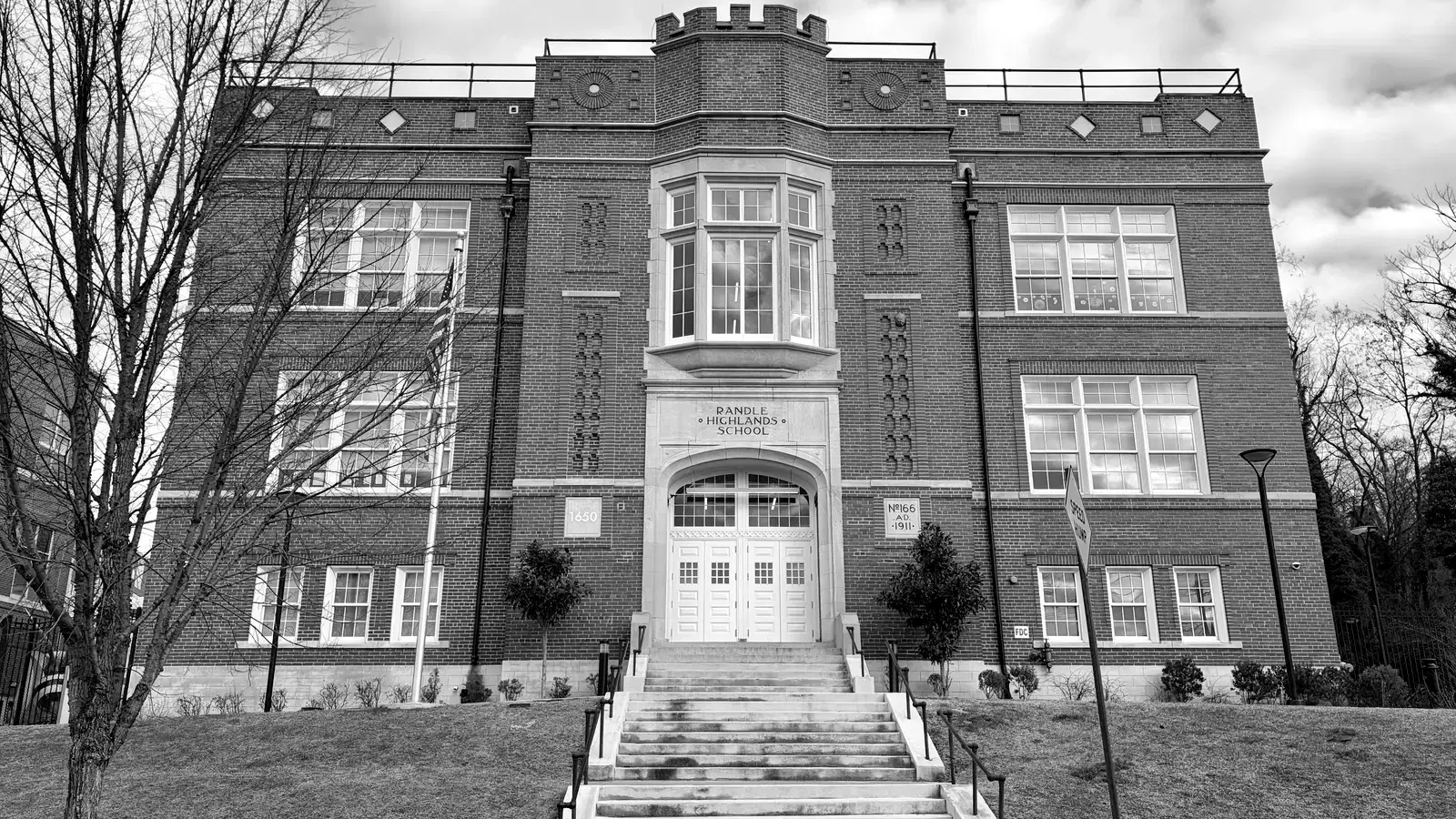 The 1911 Tudor Revival brick facade of Randle Highlands School in black and white, its name carved in stone above the arched entrance, Washington, D.C.