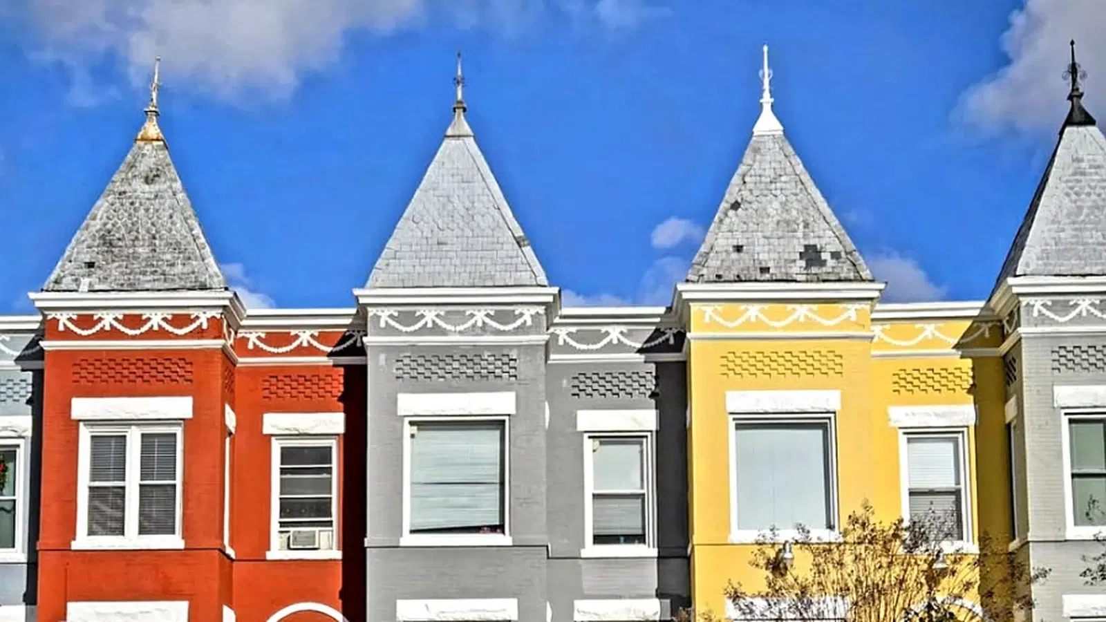 A row of turreted Trinidad rowhouses in Washington, D.C. — red, grey and yellow brick fronts with slate witch-hat turrets against a winter sky.