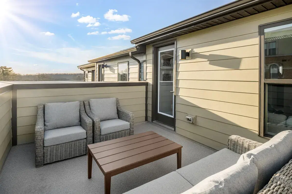 Rooftop terrace with wicker chairs and a wood table on a Clarendon townhome
