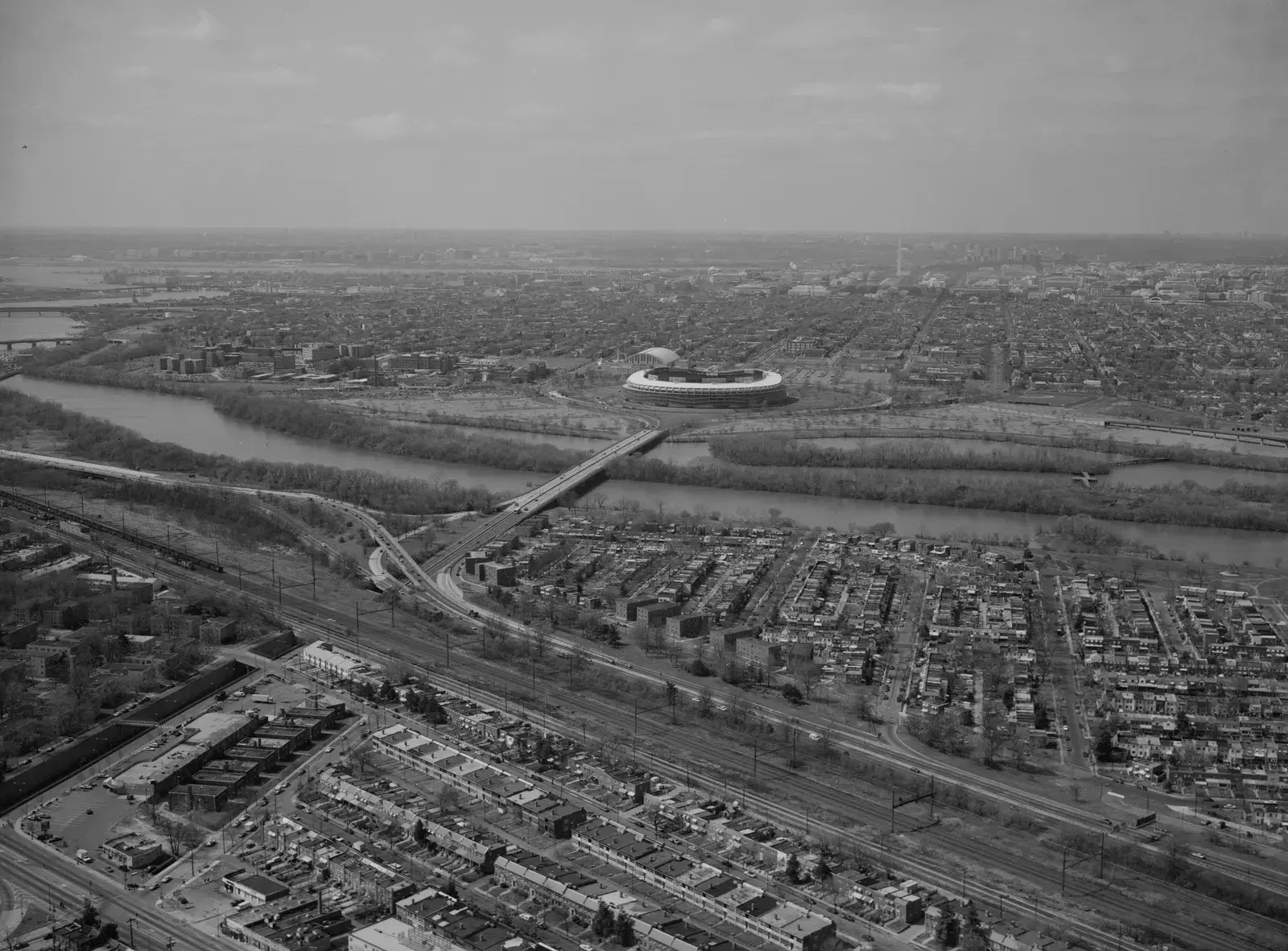 Aerial view of River Terrace's rowhouse streets beside the Anacostia and the Benning Road bridge, with RFK Stadium across the river