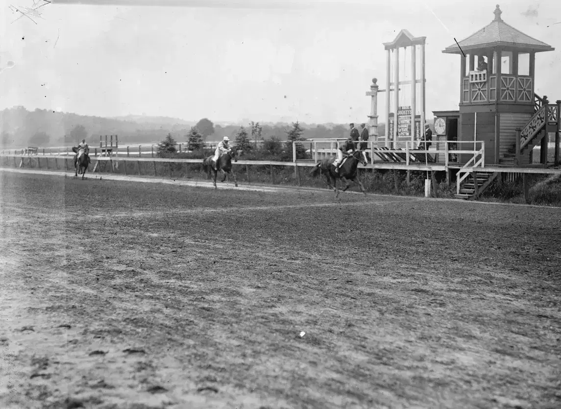 Jockeys racing horses past the judges' stand at the Benning track