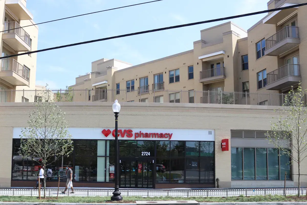 The Crest apartments above a CVS Pharmacy storefront on Marion Barry Avenue SE, with two people walking past