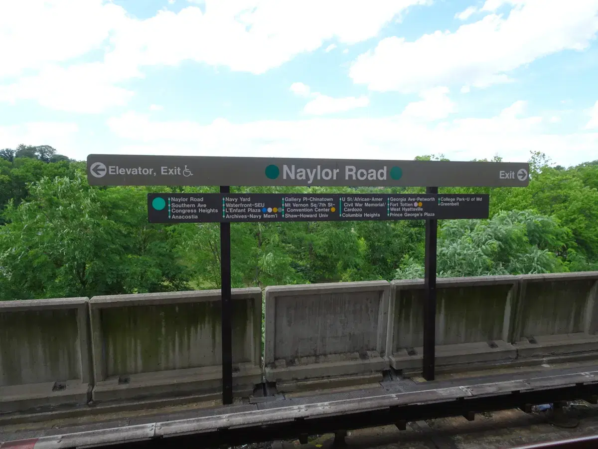 The Naylor Road station sign and Green Line map on the platform, with trees behind