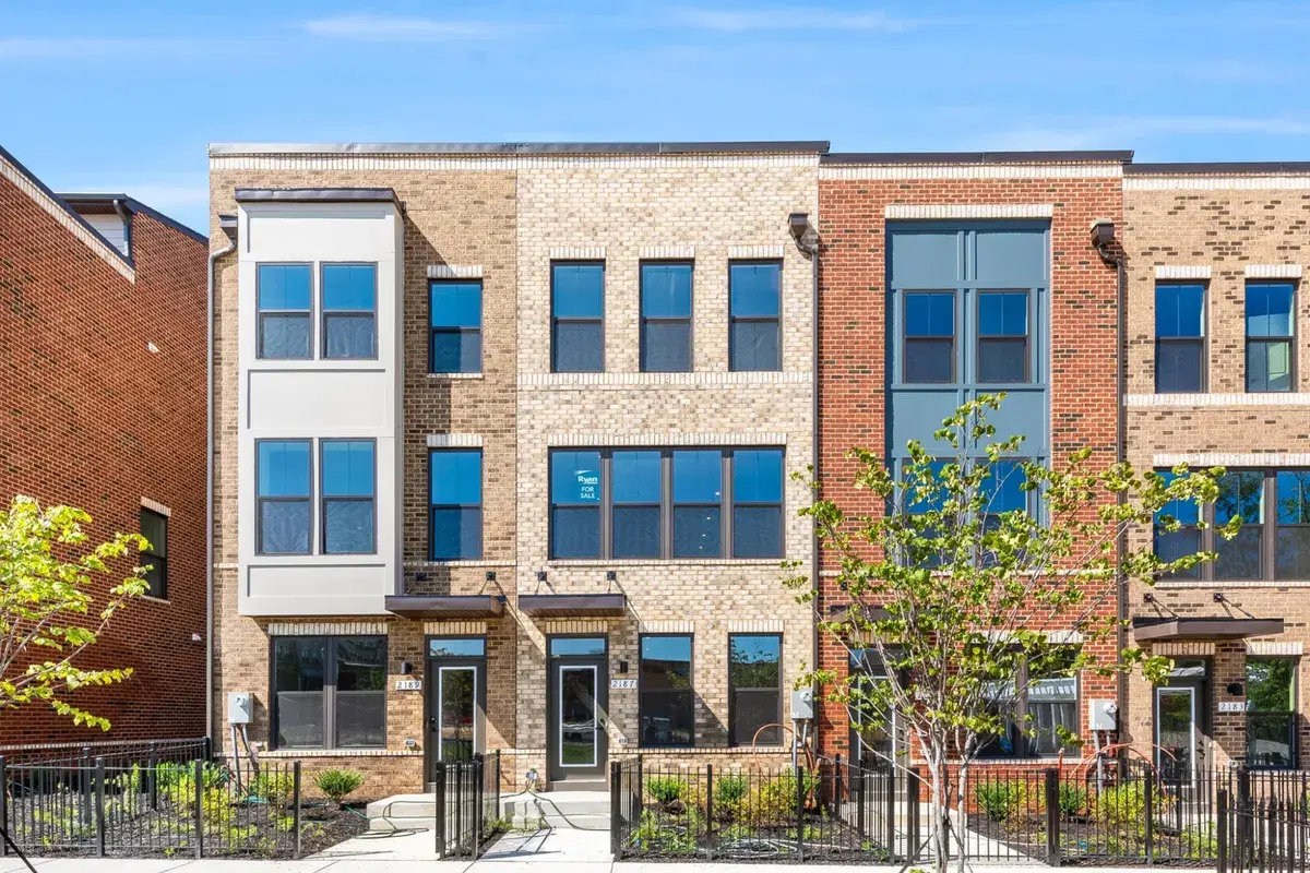 Finished brick townhomes at Skyland with a Ryan Homes for-sale sign in a window