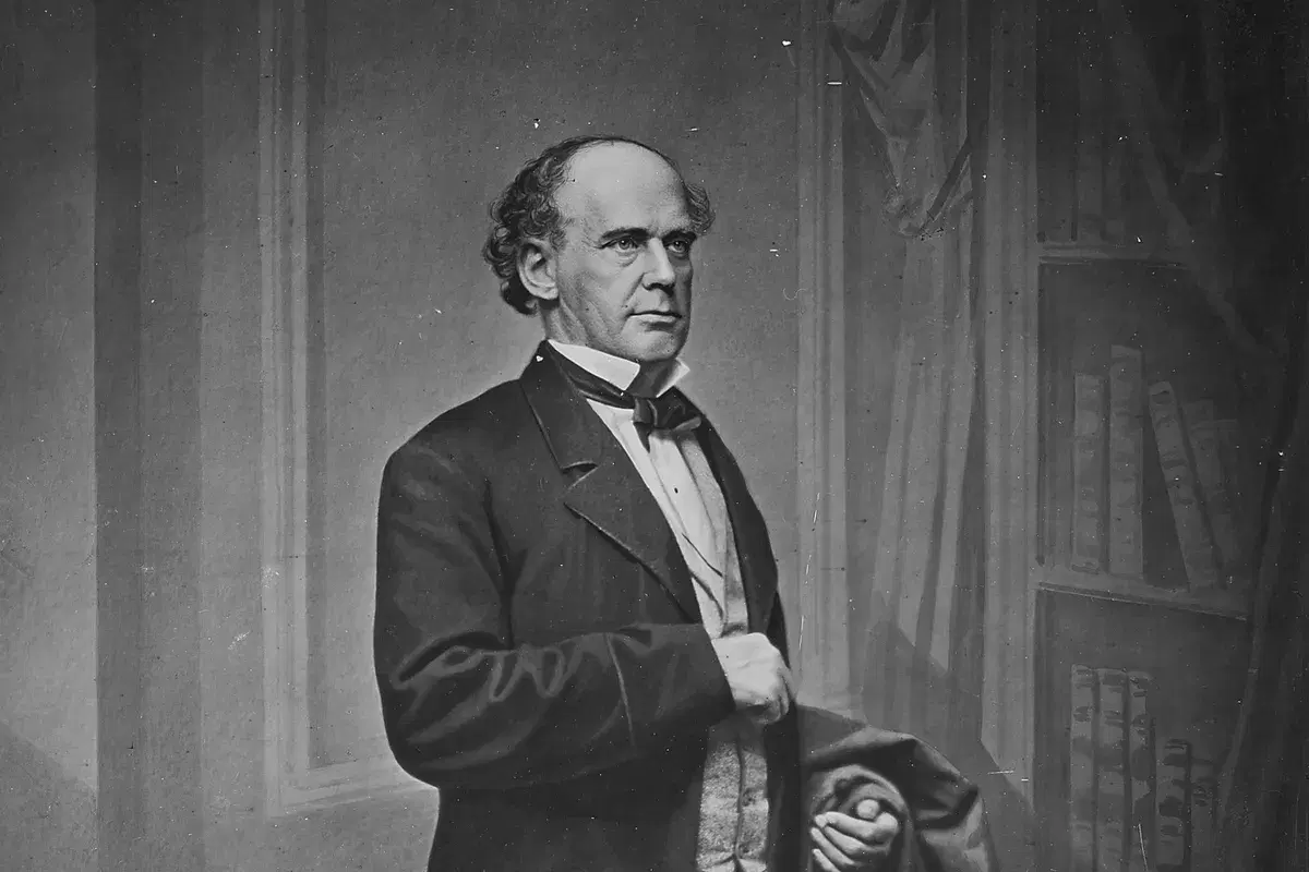 Studio portrait of Salmon P. Chase standing in a frock coat beside a bookcase