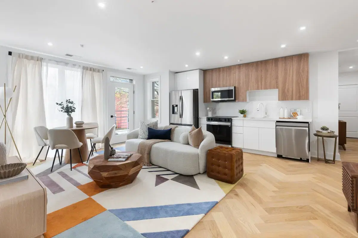 Living room and kitchen in a condo at the Sidney, with herringbone oak floors and a balcony door